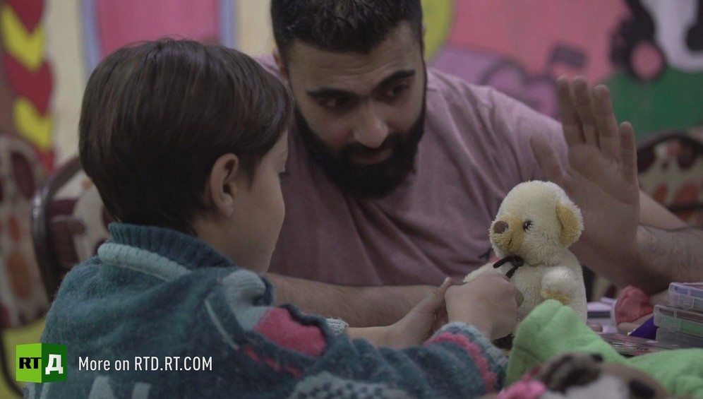 Little boy playing with teddy bear, guided by child psychologist in Aleppo Province, Syria. He was traumatised after being forced to watch beheadings by rebel fighters from Jaish Al Islam. Still taken from RTD documentary about child fighters Where Childhood Died.