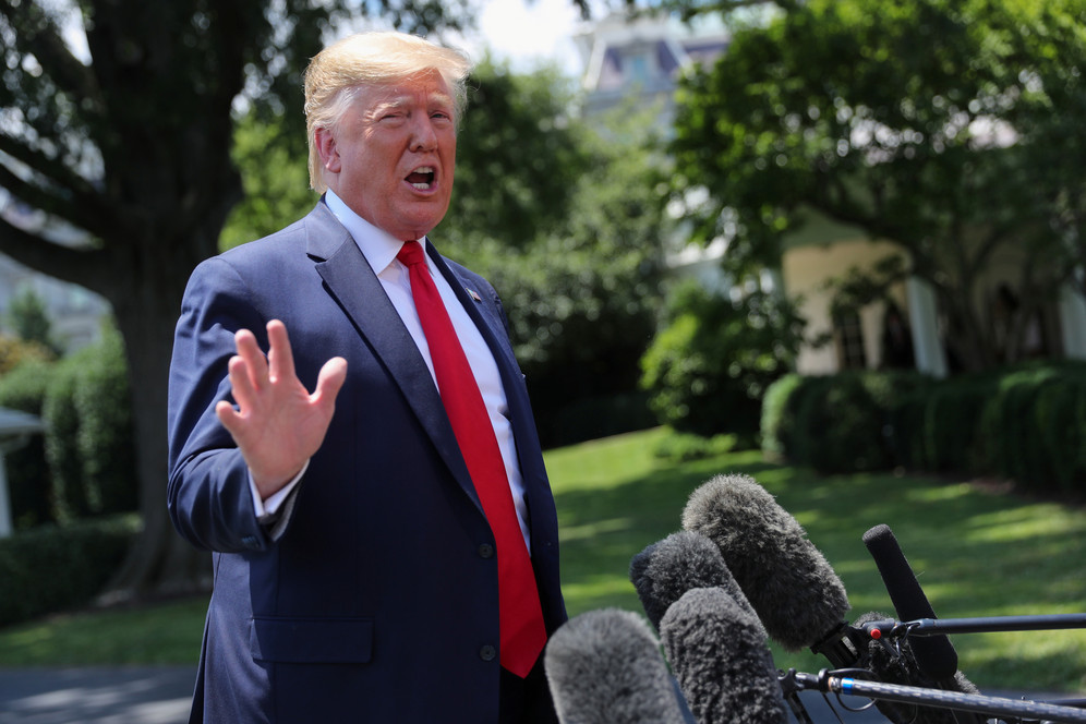 Donald Trump standing with hand outstretched.