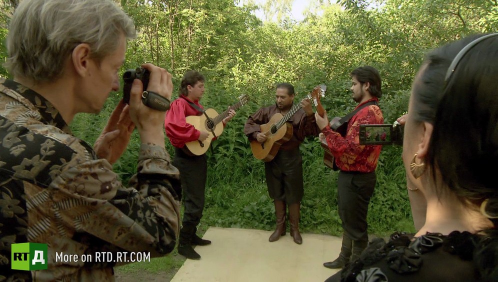 A man and a woman film Gypsy guitarists playing traditional Gypsy songs in Russia.